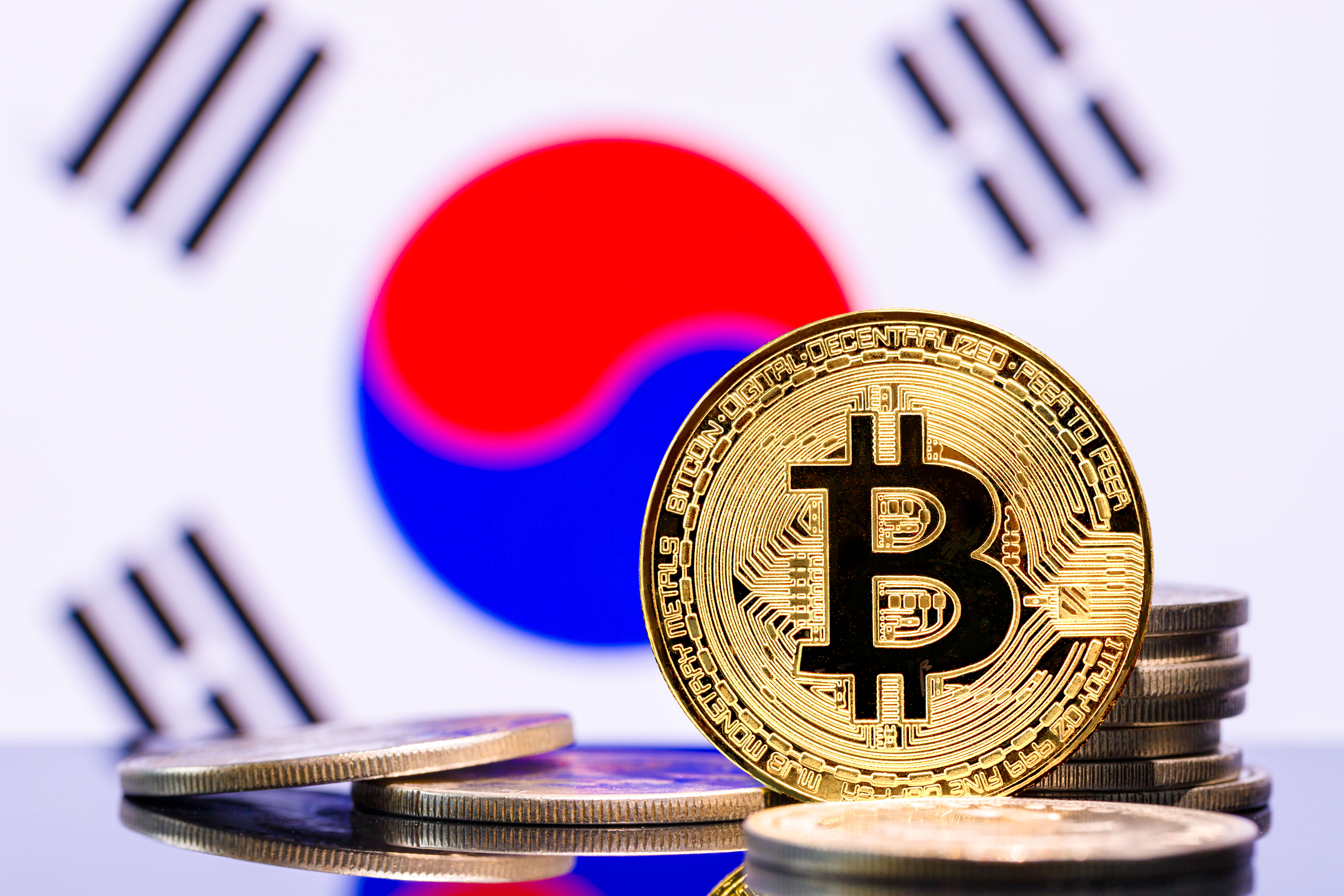 An image showing a representation of a bitcoin token against the backdrop of a South Korean flag.