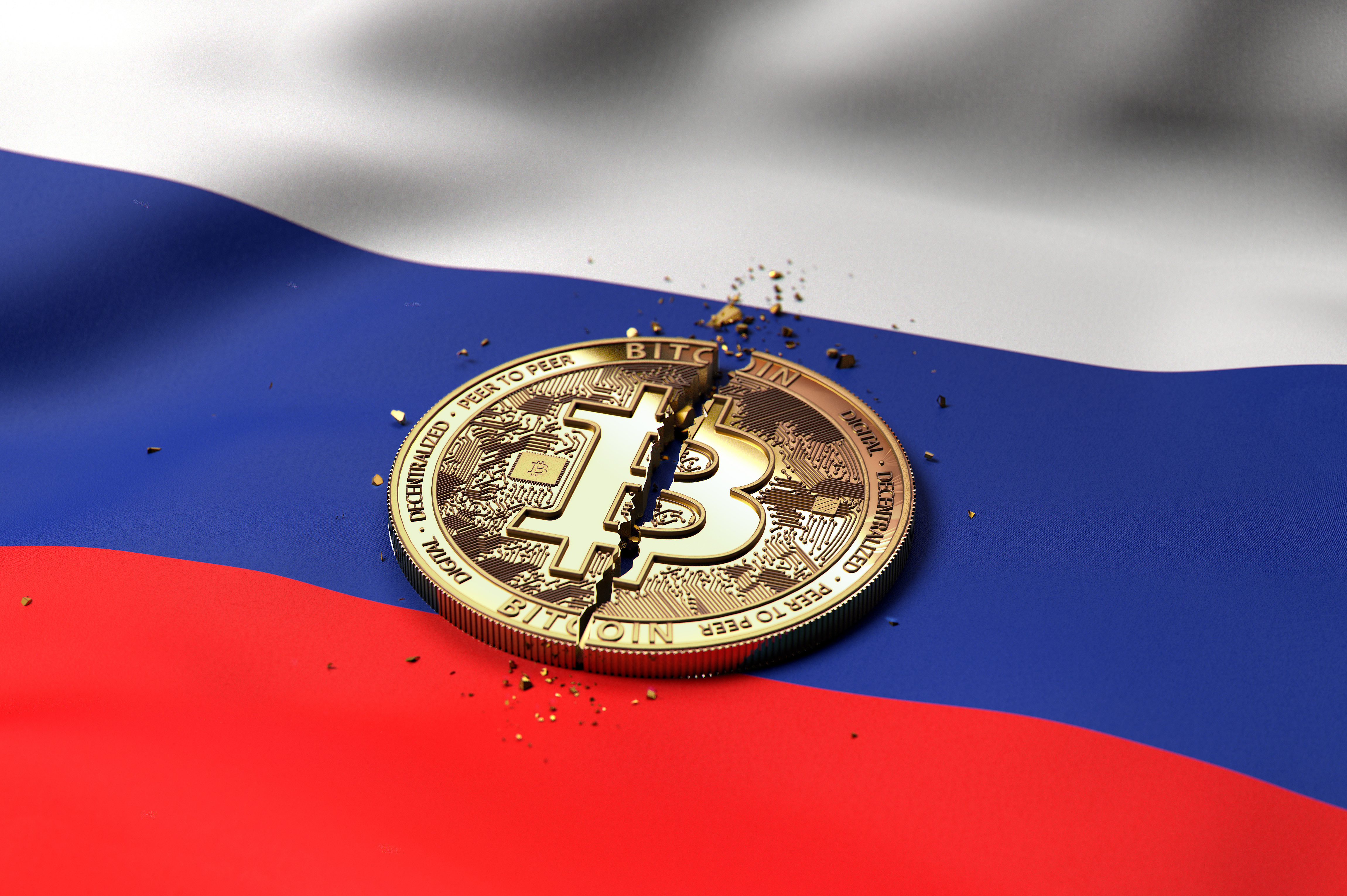 A cracked token representing Bitcoin rests on a Russian flag.