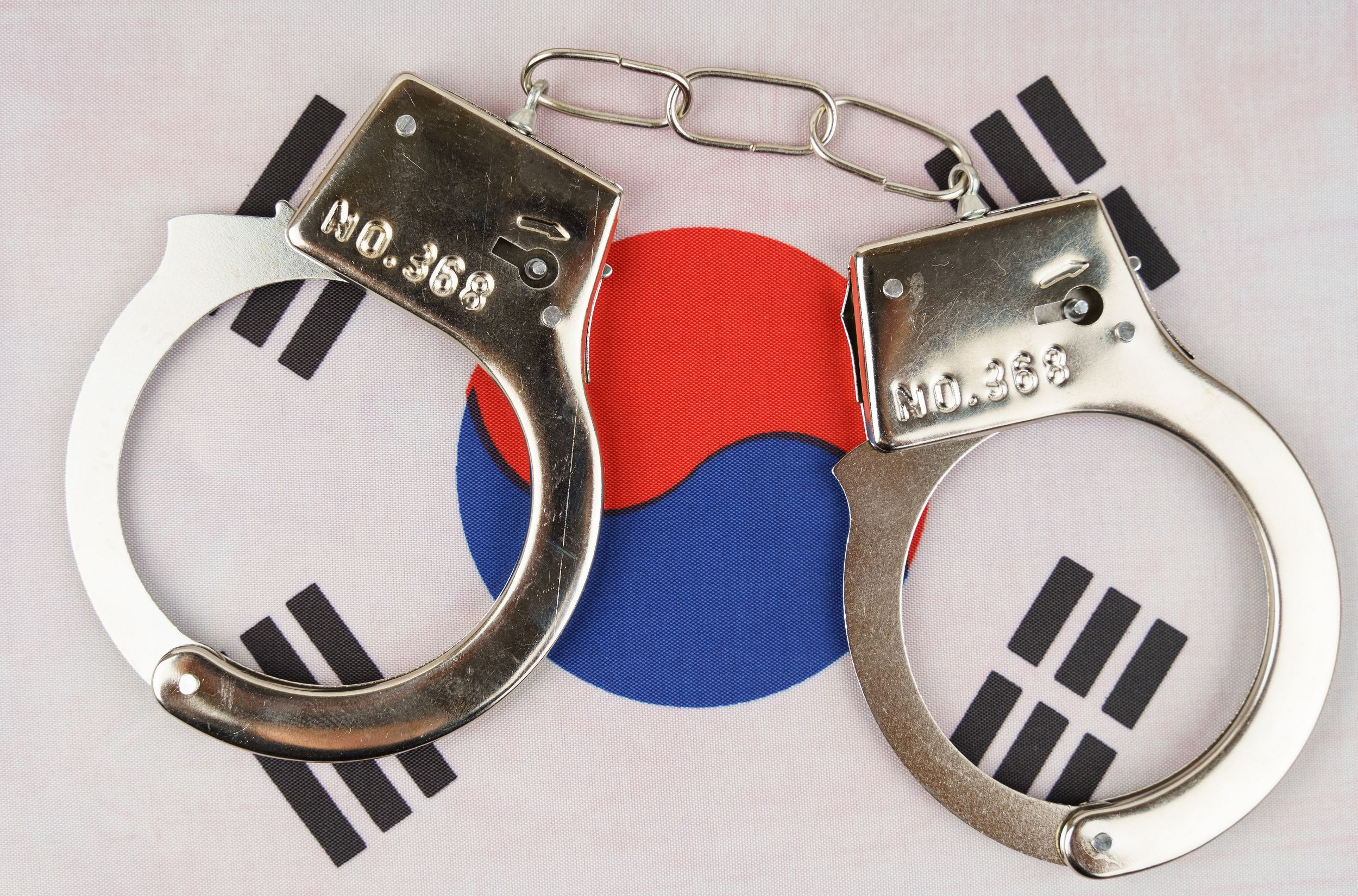 A pair of handcuffs rests on the flag of South Korea.