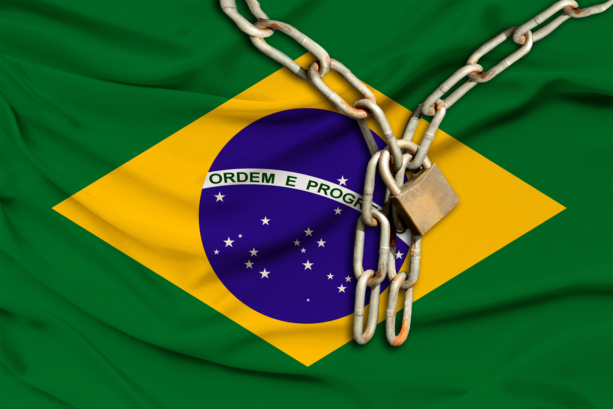 A metal chain and padlock rest on a Brazilian flag.