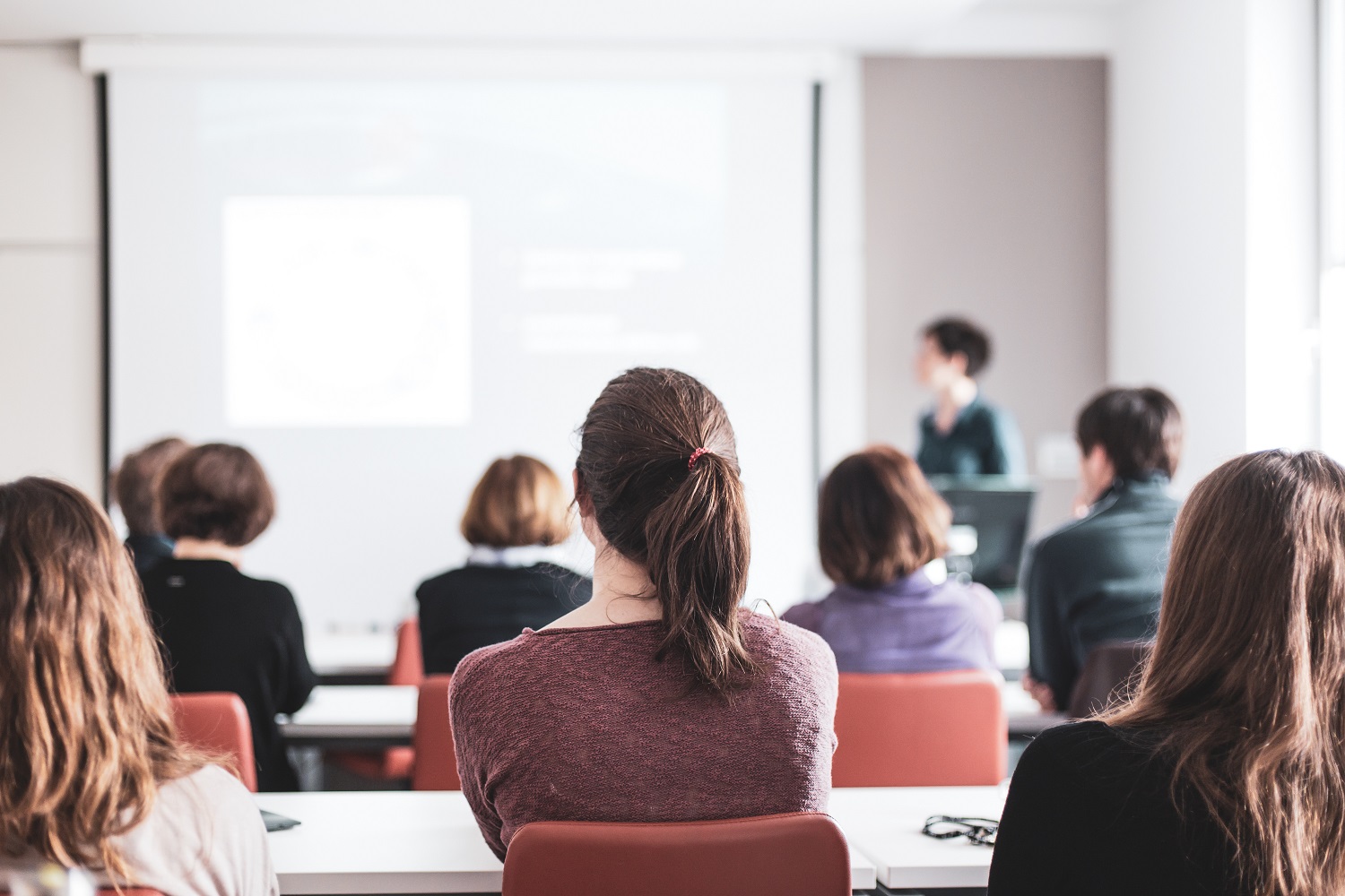 A lecturer gives a presentation in a lecture hall at a university as students sit and listen.