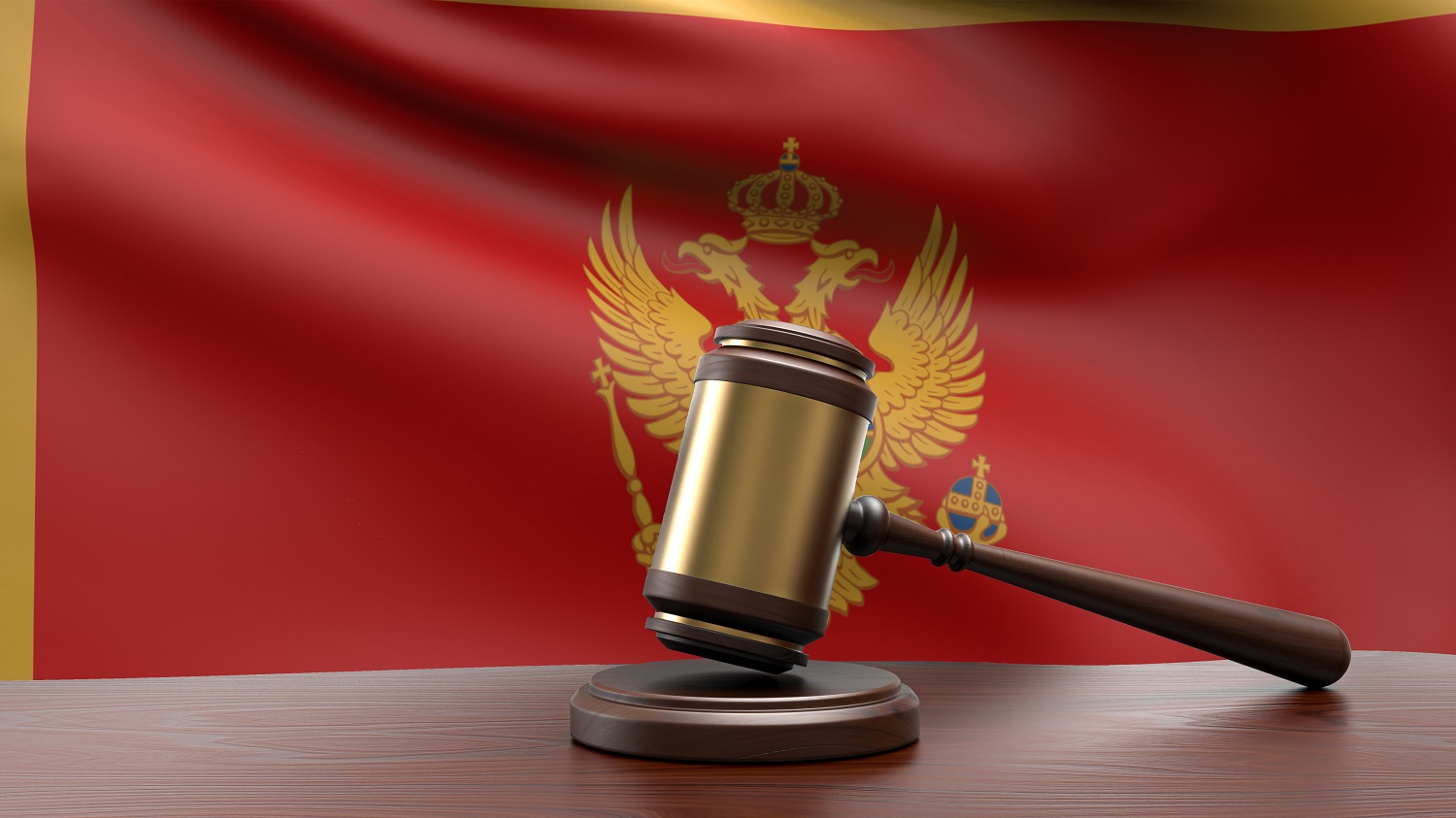 A judge’s gavel and block on a desk in front of the Montenegro national flag.
