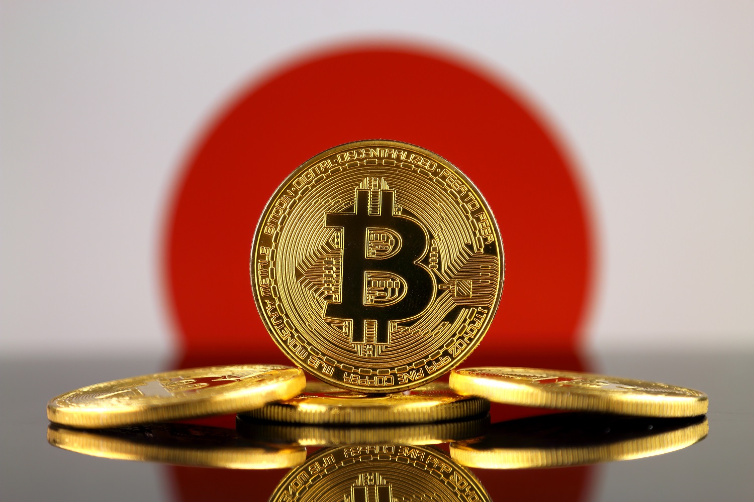 Five metal tokens intended to represent Bitcoin against the backdrop of the Japanese flag.