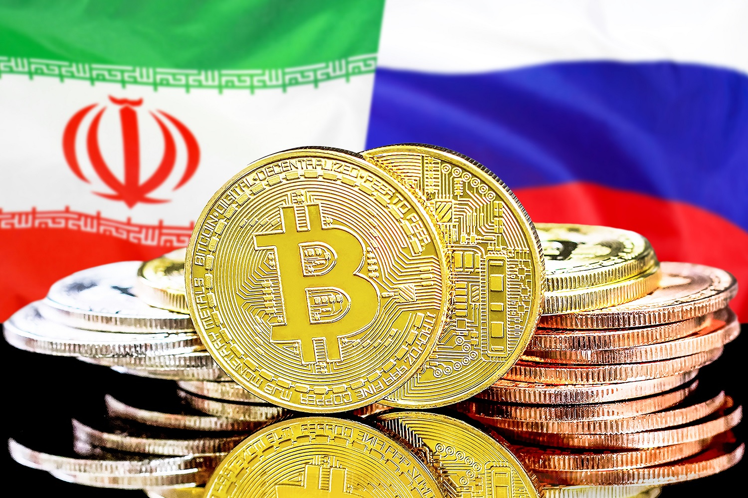 A pile of metal coins intended to represent Bitcoin tokens against the background of the flags of Iran and Russia.