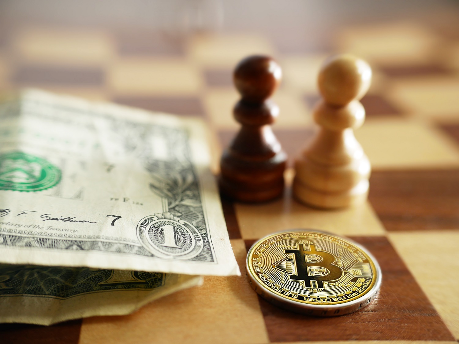 Kim loại token dự định đại diện cho Bitcoin bên cạnh các tờ đô la Mỹ trên bàn cờ với các quân cờ.