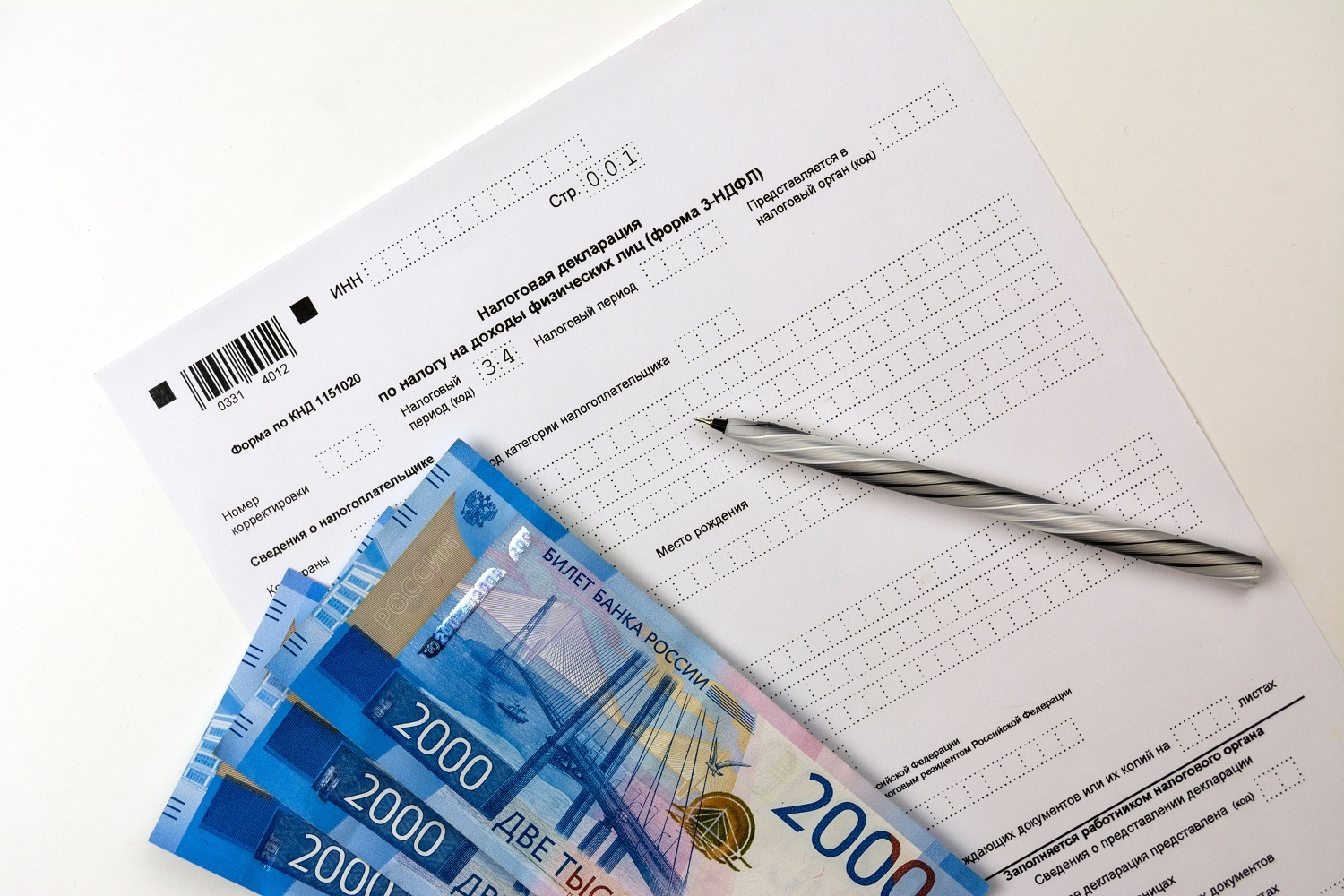 A blank copy of the Russian tax return form, ruble banknotes and a pen rest on a table.