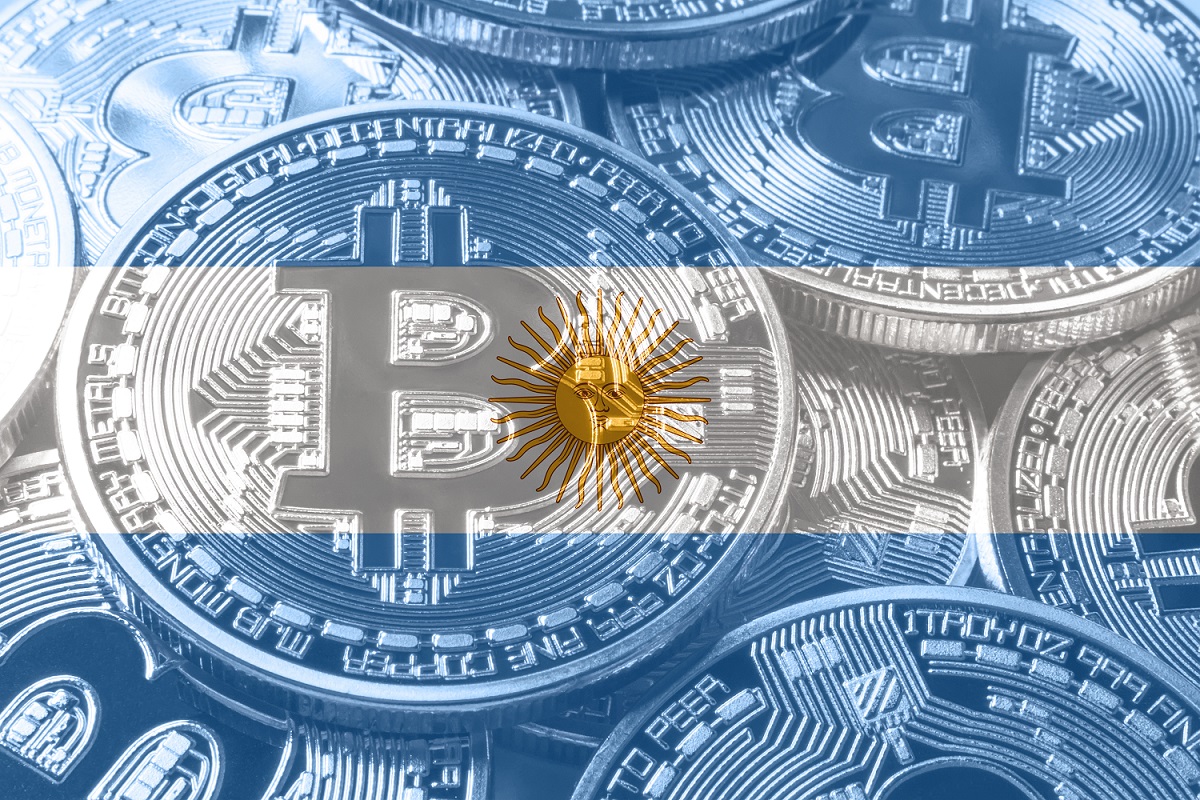 Một đống tiền kim loại nhằm đại diện cho Bitcoin được đặt chồng lên hình ảnh lá cờ của Argentina.