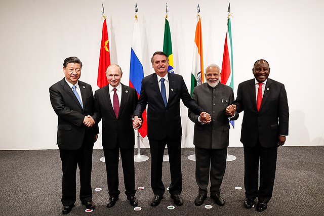 The five leaders of the BRICS nations join hands in front of their nation’s flags at a meeting in 2019.