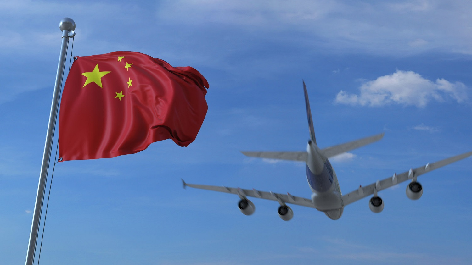 A commercial plane flies behind a Chinese flag waving in the wind.