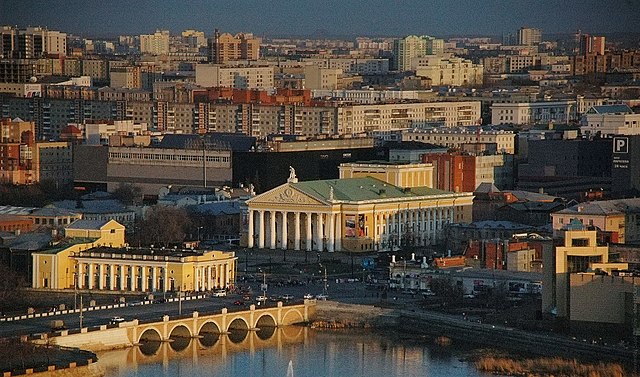 A river flows in front of the Chelyabinsk state theater of opera and ballet.