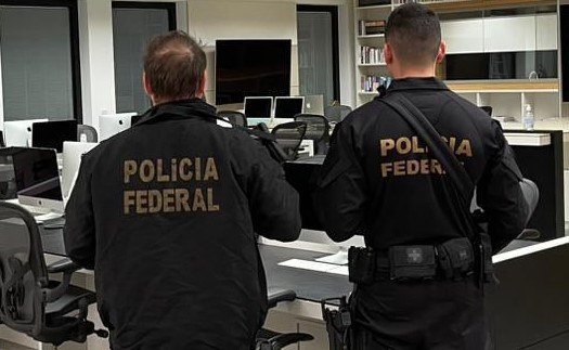 Police officers in uniform stand in an office space during recent raids on a Braiscompany-linked address.