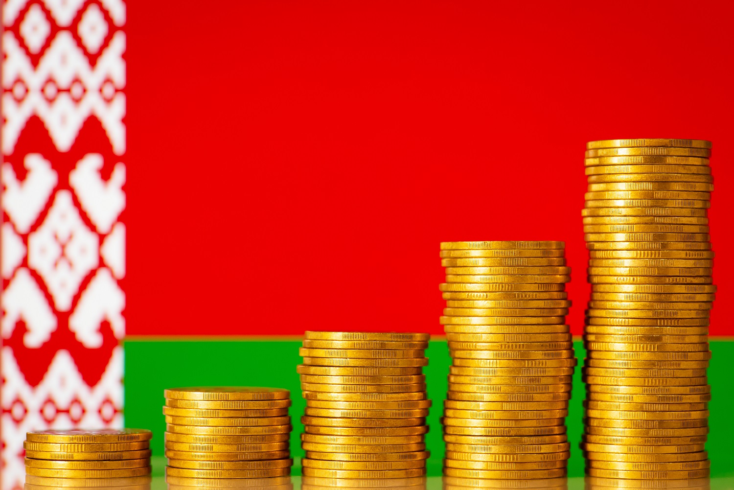 Stacks of metal coins against the backdrop of the flag of Belarus.