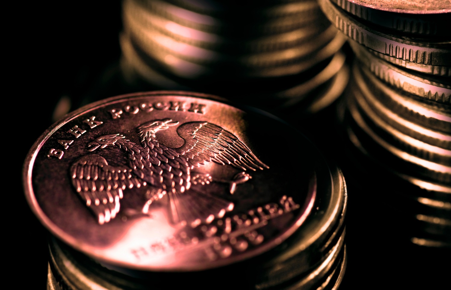 Three piles of Russian ruble coins, featuring the Russian double-headed eagle crest and the words “Bank of Russia” in Russian.