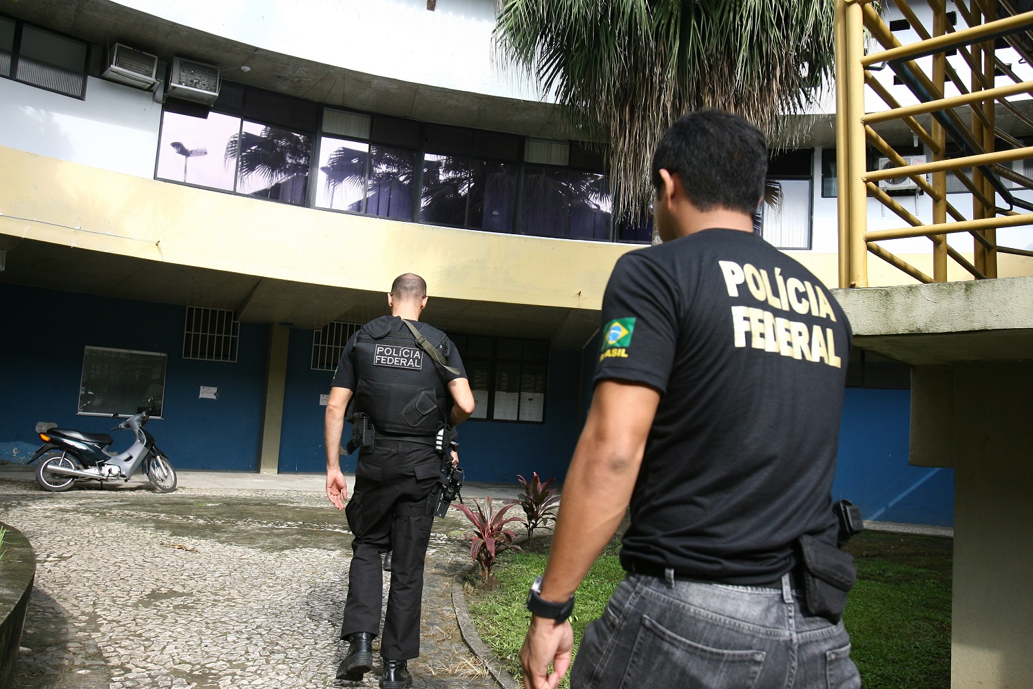 Two Federal Police officers in Brazil approach a building.