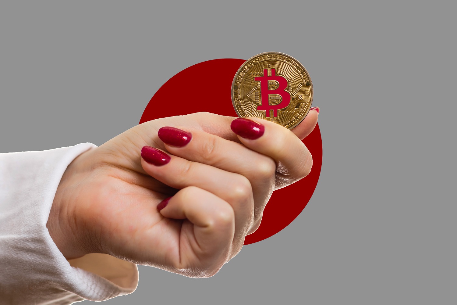 A woman’s hand holds a token intended to represent Bitcoin against the background of the flag of Japan.