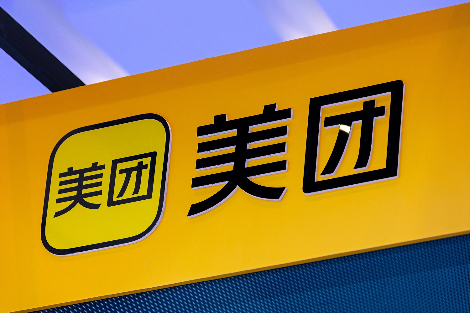 A yellow sign emblazoned with the logo of the Chinese e-commerce firm Meituan.