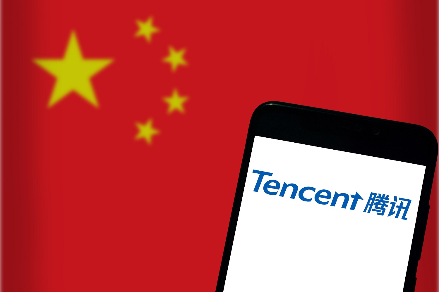 The Tencent logo on a mobile phone screen against the background of a Chinese flag.