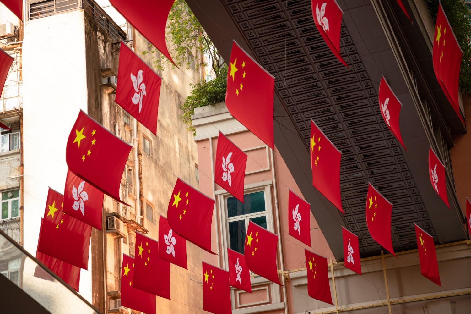 Flags of the People’s Republic and Hong Kong hang in a public street.