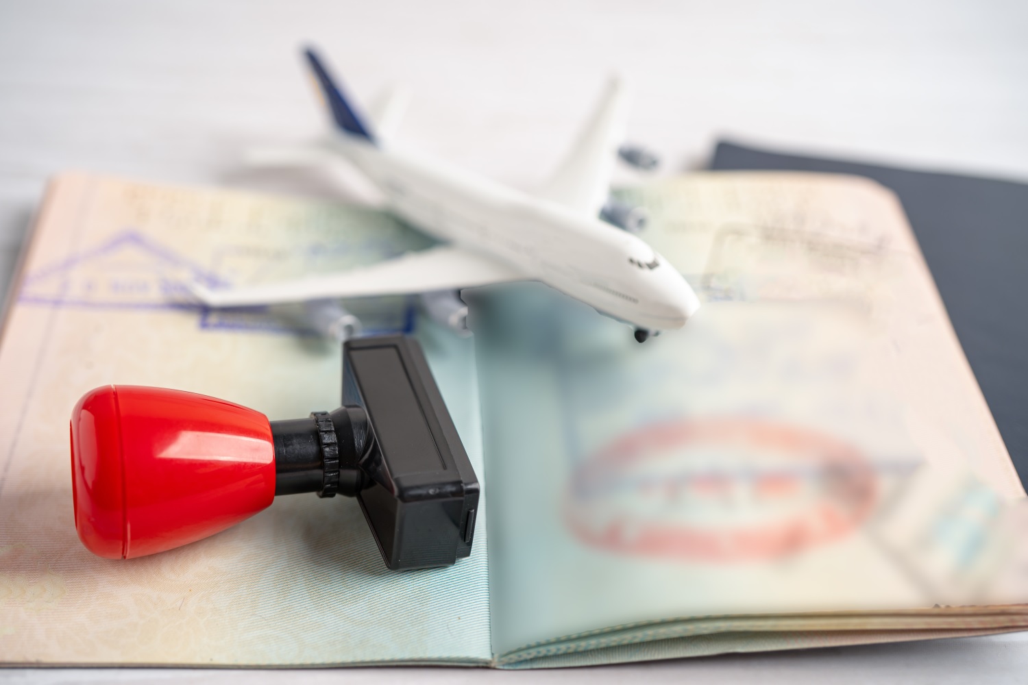 A visa stamp and an open passport, topped with a small model aircraft.