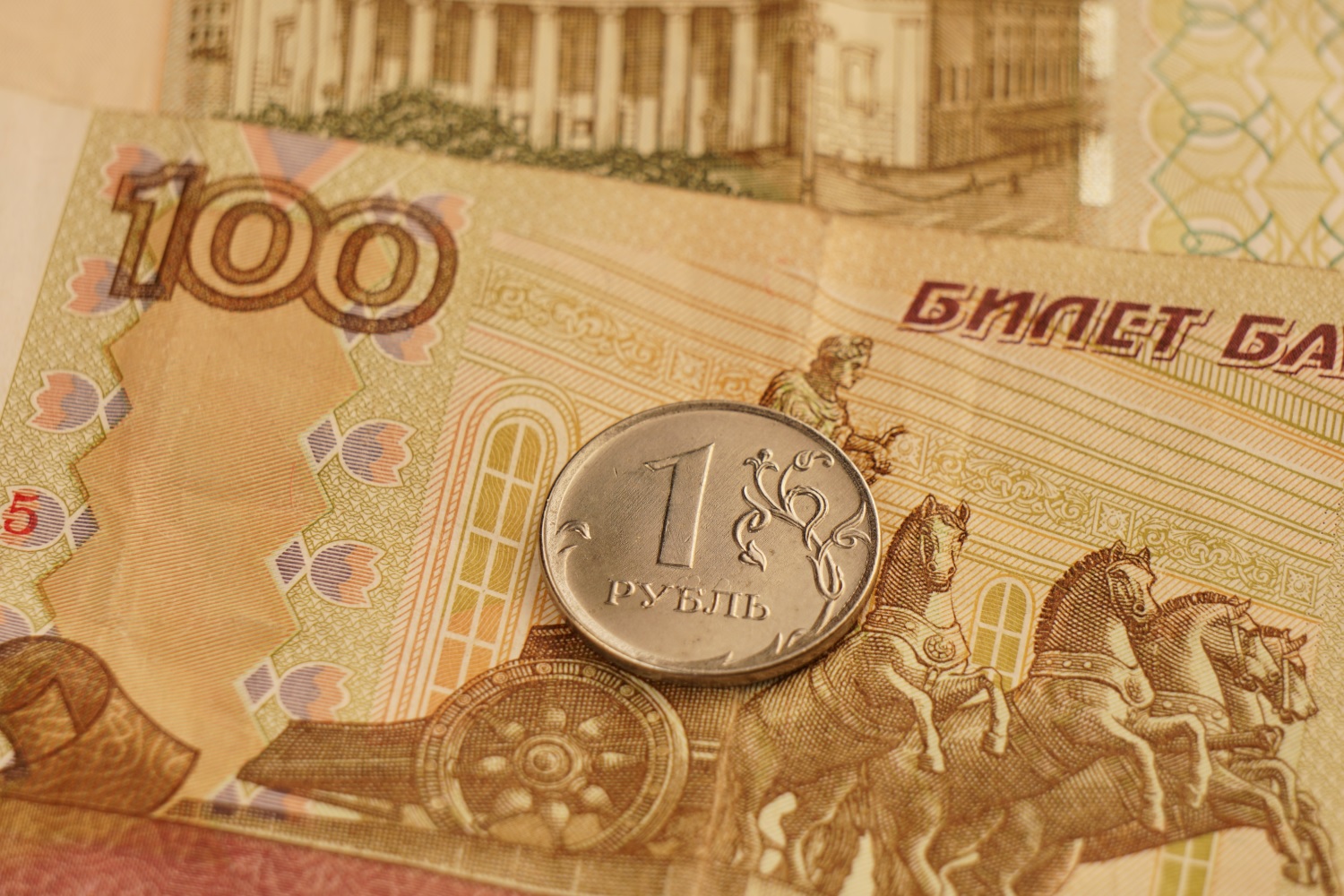 A one-ruble coin rests on Russian paper banknotes.