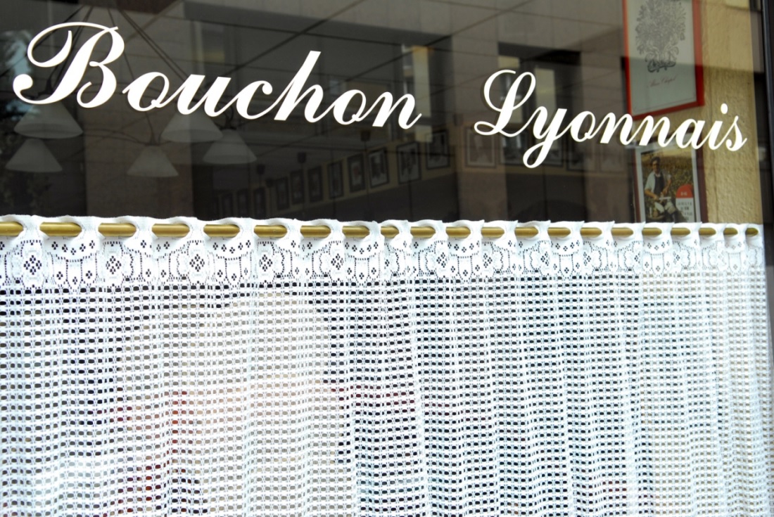 The exterior of a restaurant with the text Bouchon Lyonnais on its window.
