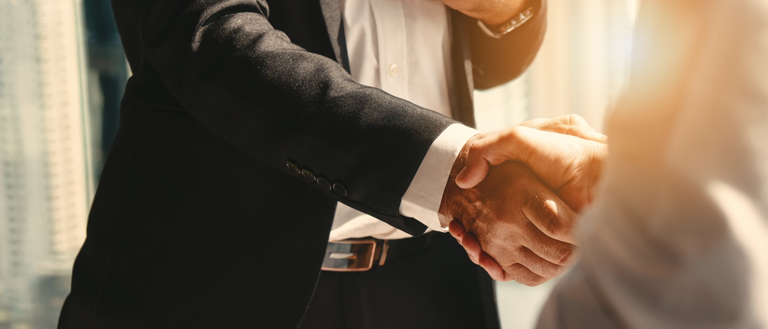 Two people in business attire shake hands.