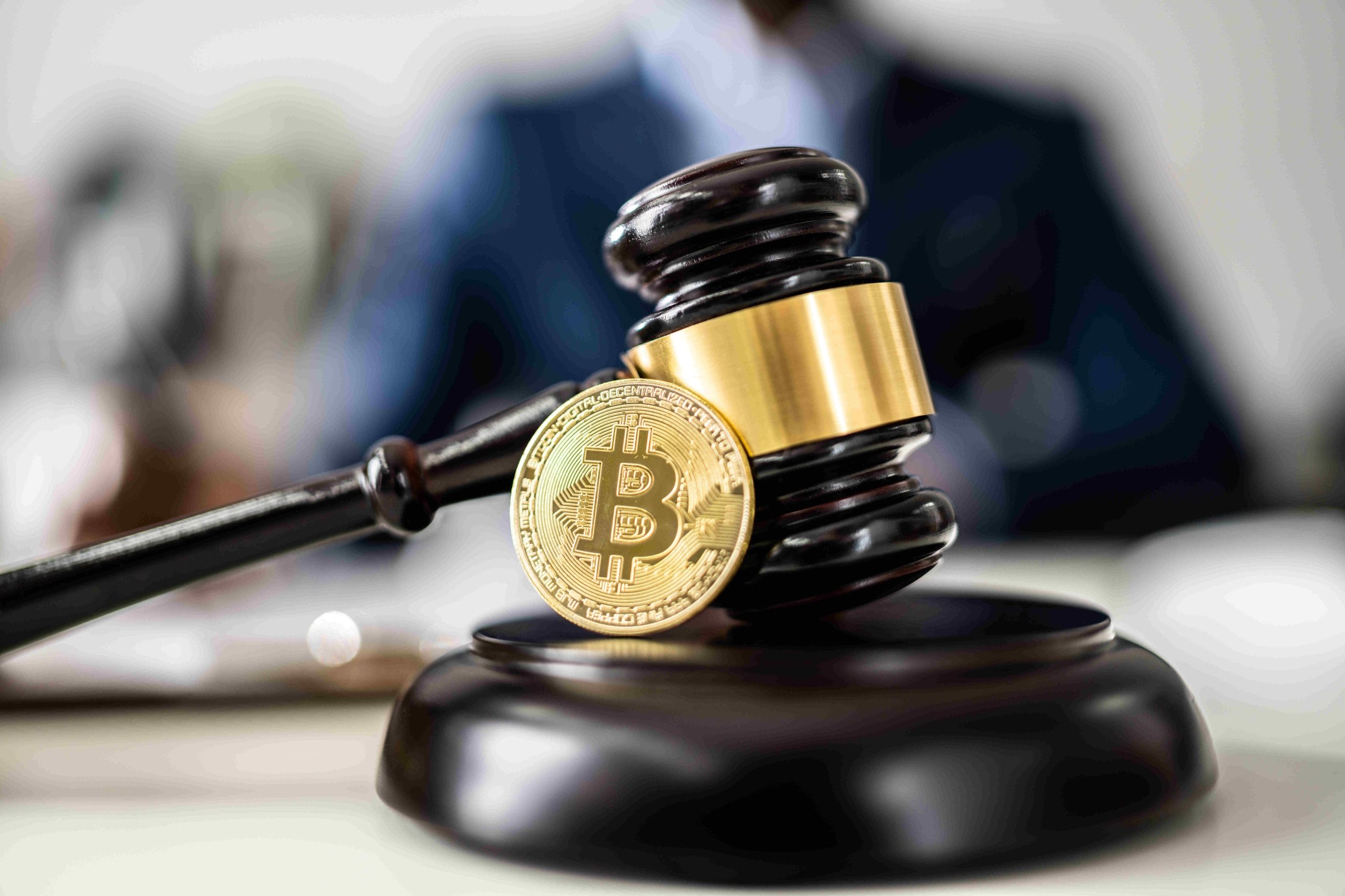 A Bitcoin cryptocurrency coin symbolically placed on a wooden judge's gavel, representing Coinbase's case against the SEC in a legal setting.