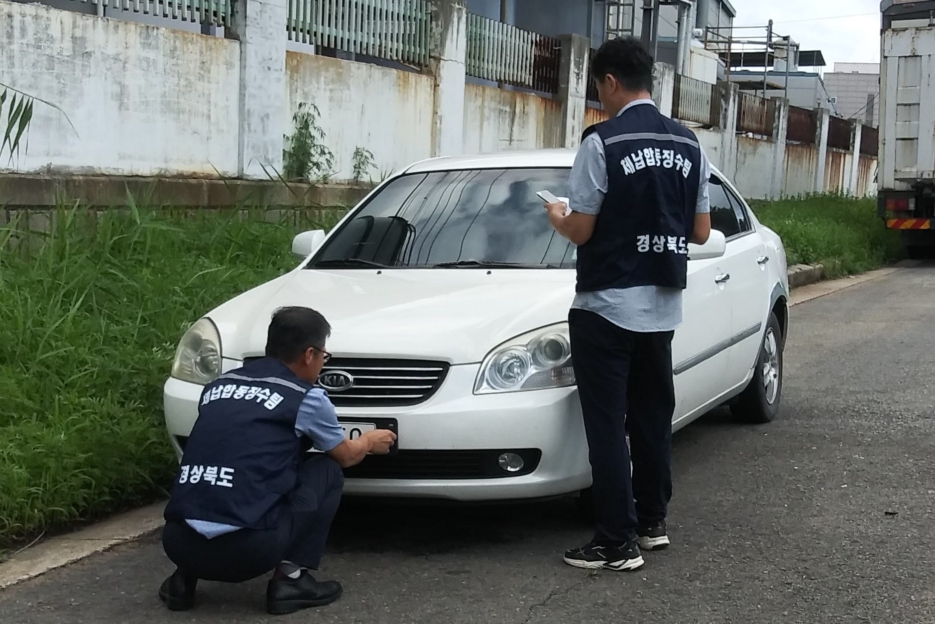Officials from Yeongcheon’s local authority remove a car license plate as part of unpaid tax-related asset seizures.