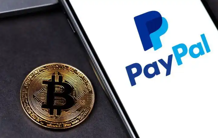 PayPal logo on the screen smartphone with bitcoin cryptocurrency on black background.