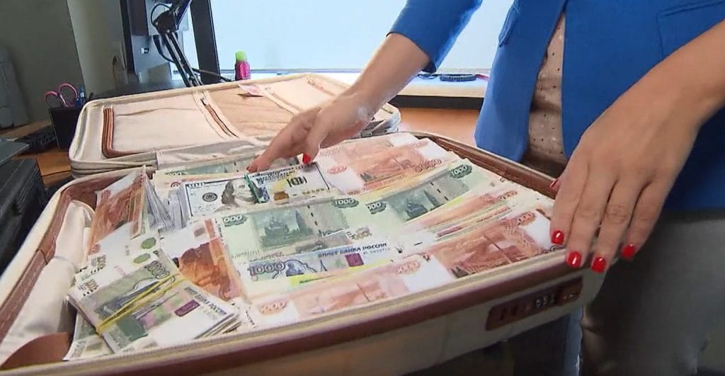 A news reporter demonstrates how much money could fit into the kind of “cash-filled suitcases” Bitmama’s offices allegedly received from customers.