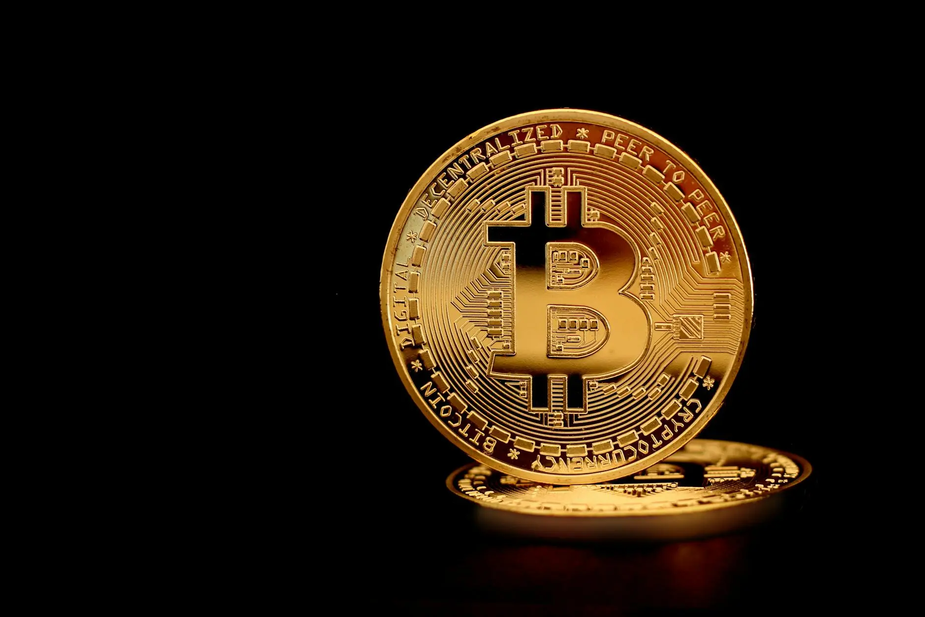Three gold Bitcoin coins displayed against a black background.