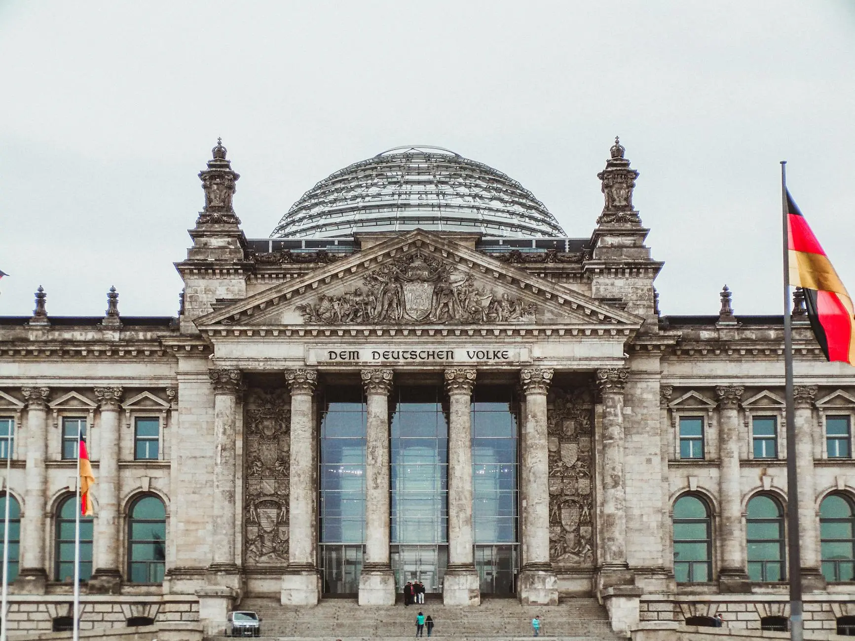 Facade of the Reichstag building in Berlin, Germany, featuring its dome and flags.