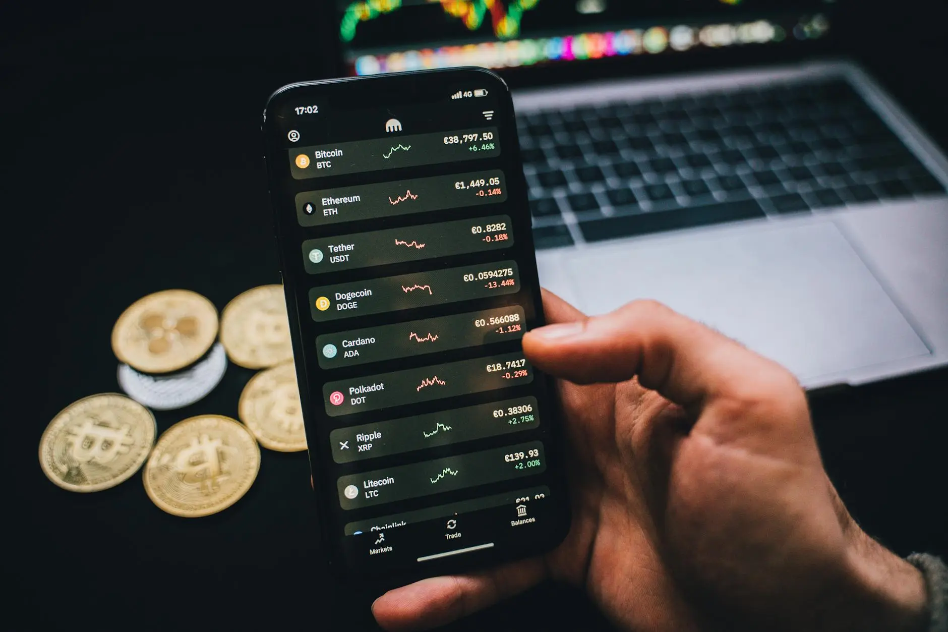 A hand holding a smartphone displaying cryptocurrency prices, with Bitcoin and Ethereum listed.