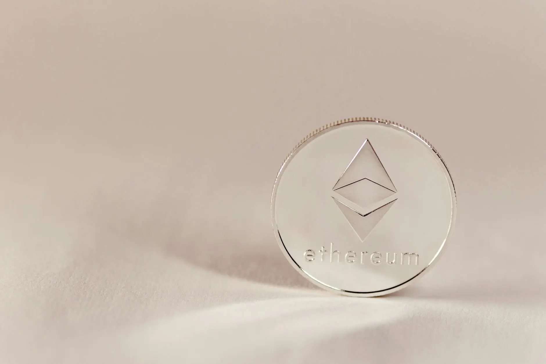 A silver Ethereum coin with the logo and 'ethereum' engraved on it.