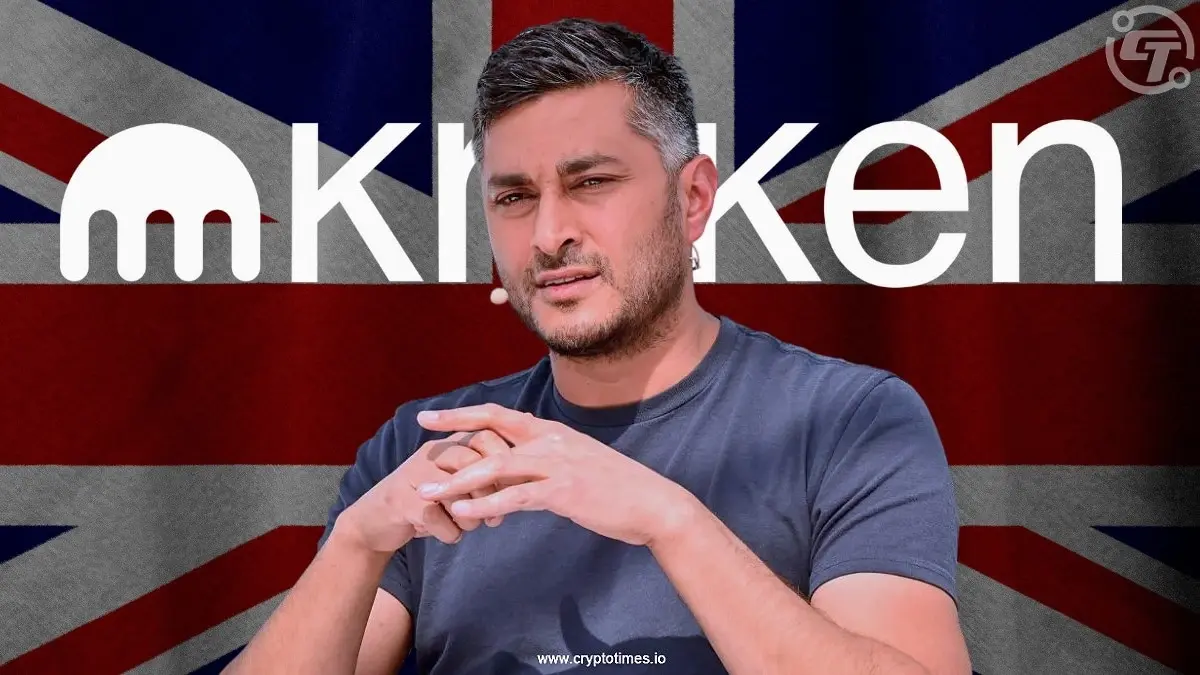 A man in a blue shirt sits in front of a Kraken logo and UK flag background.