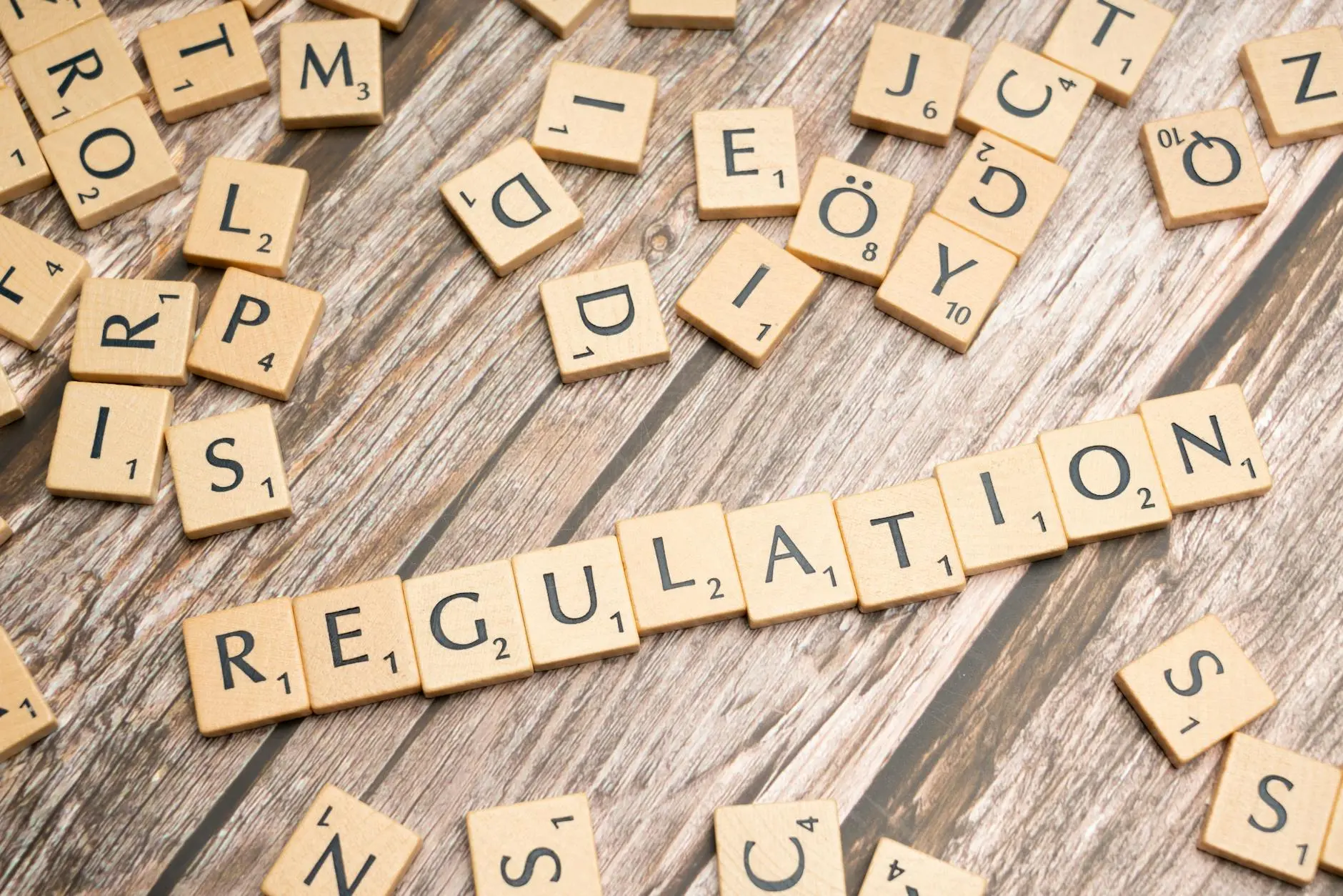 Scrabble tiles spelling 'REGULATION' on a wooden surface with other letters scattered.