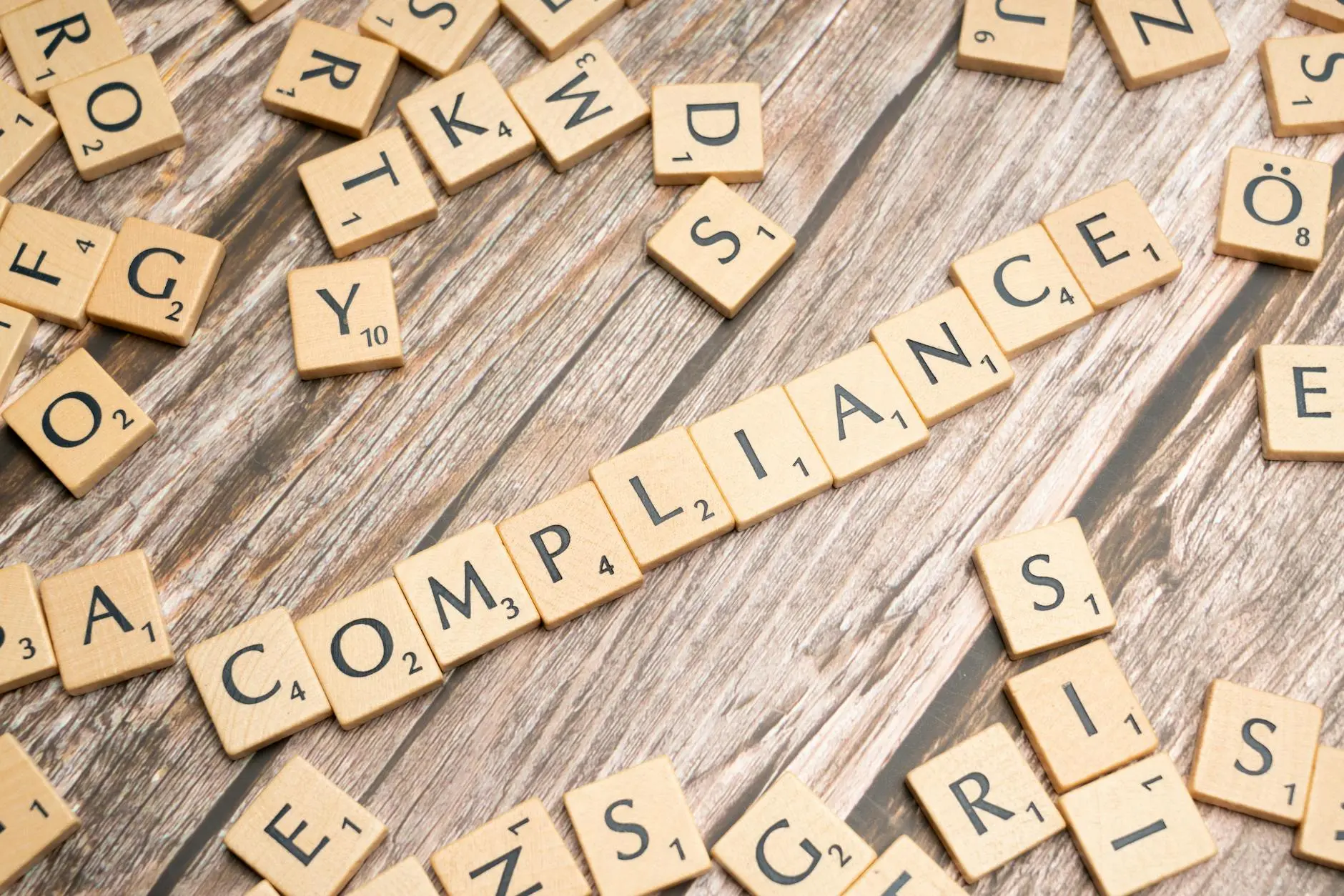 Scrabble tiles spelling 'COMPLIANCE' on a wooden background.