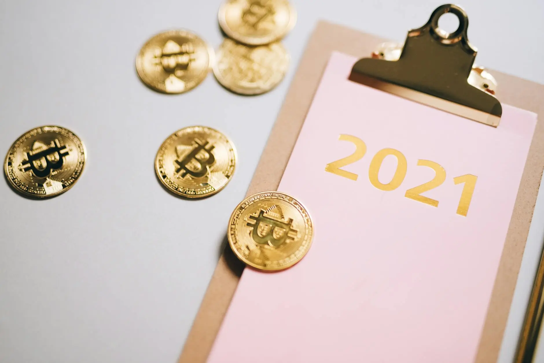 Gold Bitcoin coins next to a clipboard showing the year 2021.
