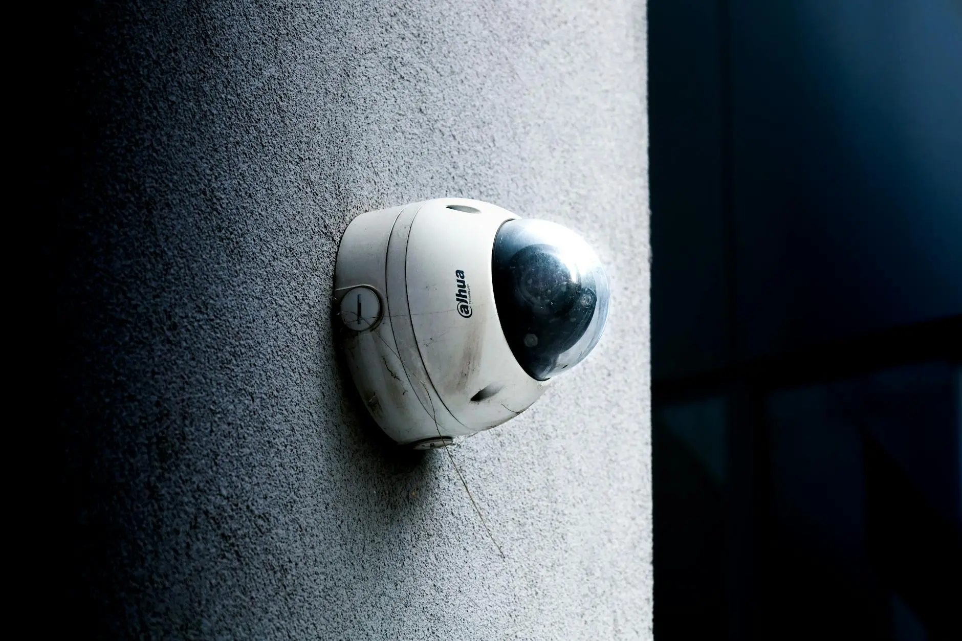 A security camera mounted on a textured wall, capturing surveillance footage.
