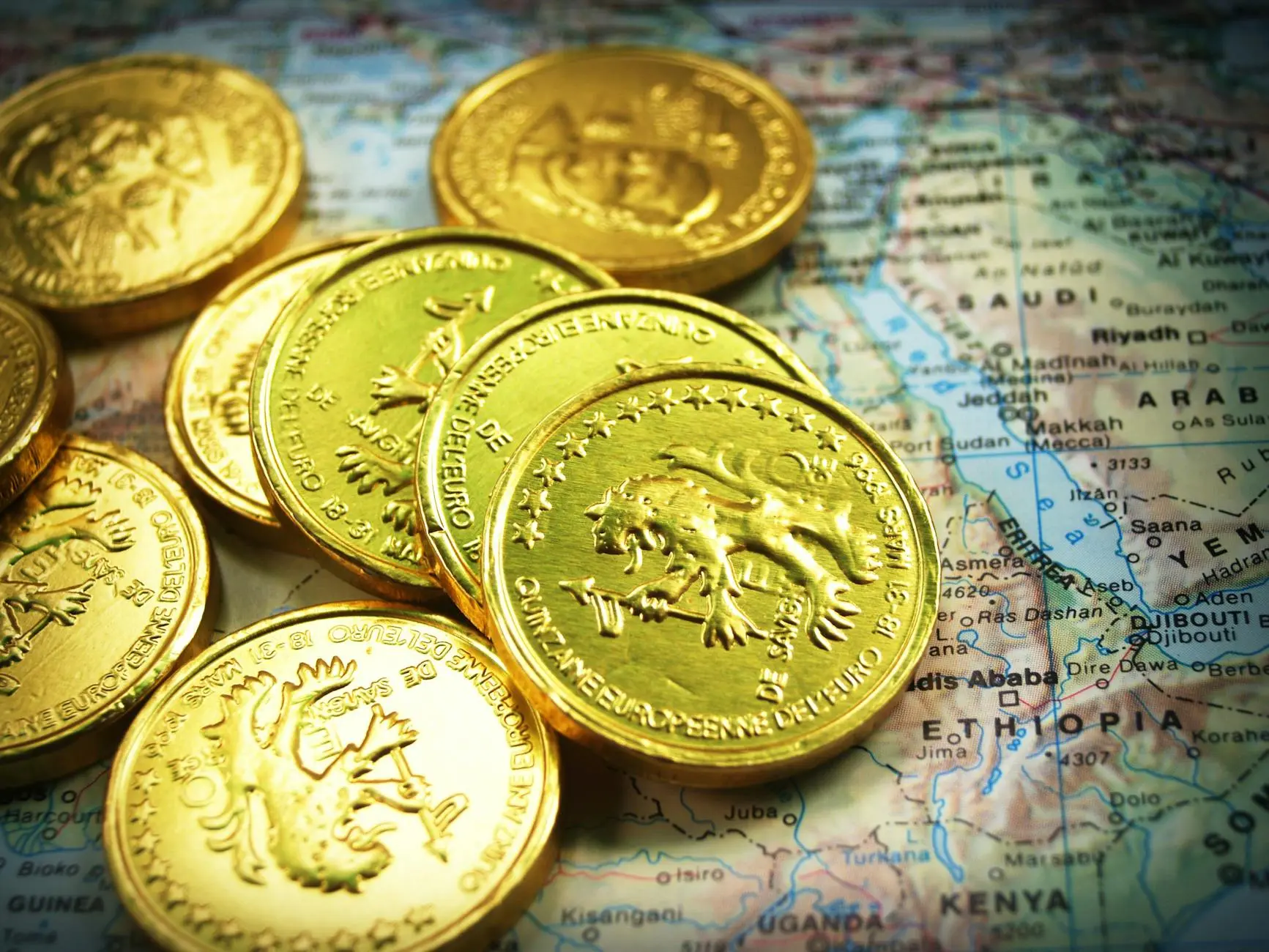 Gold coins on a map of Africa and the Middle East, highlighting regional geography.