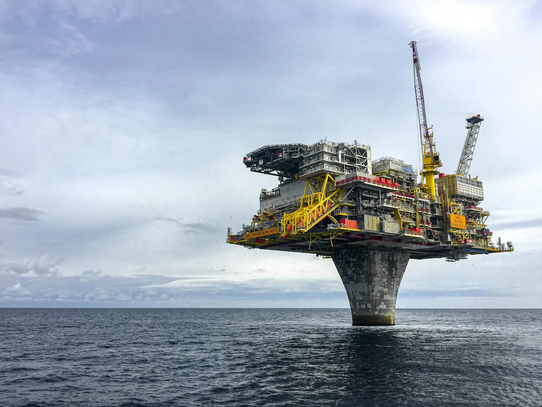 Offshore oil platform situated above the ocean under a cloudy sky.