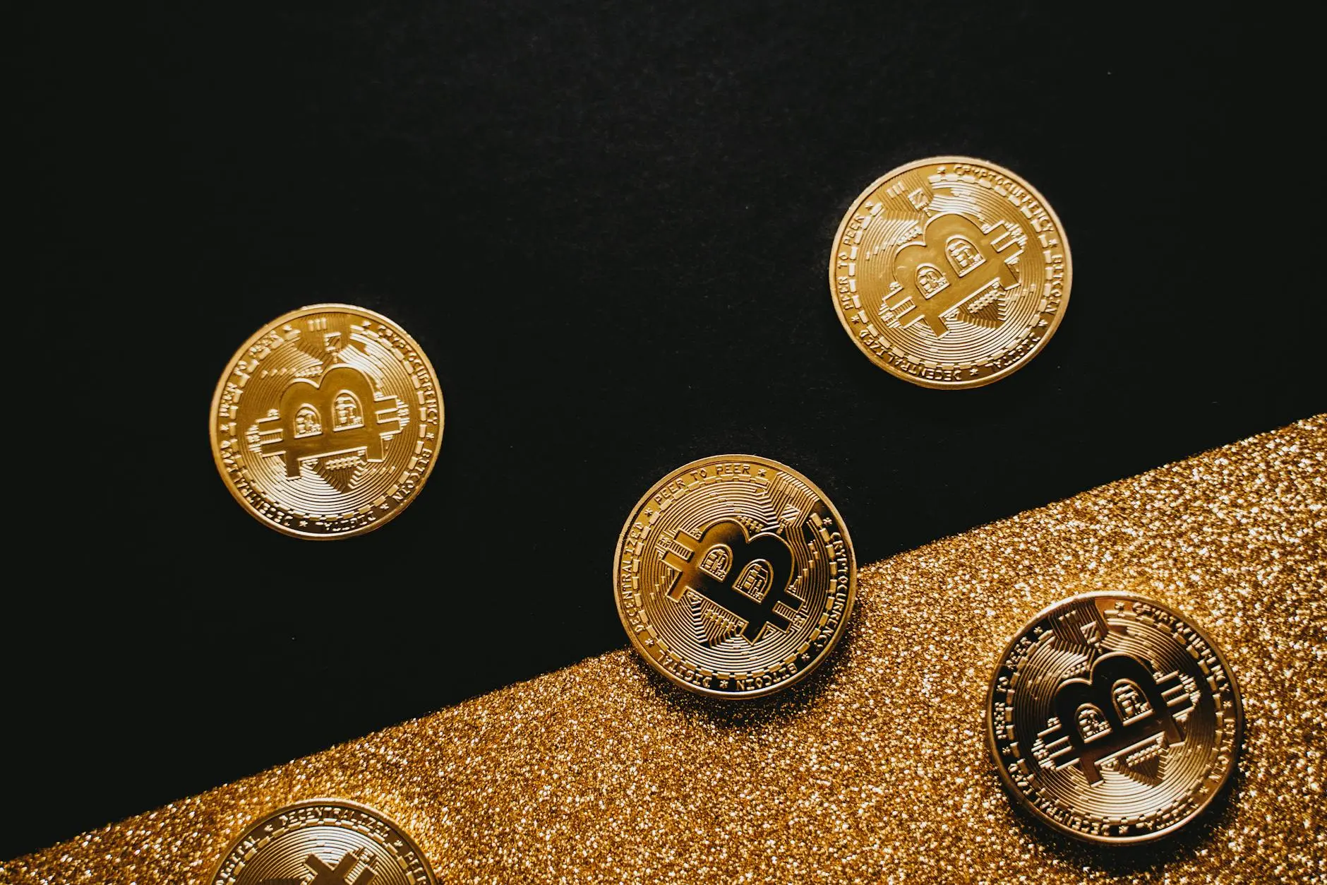 Bitcoin physical coins on a glittery gold and black background.