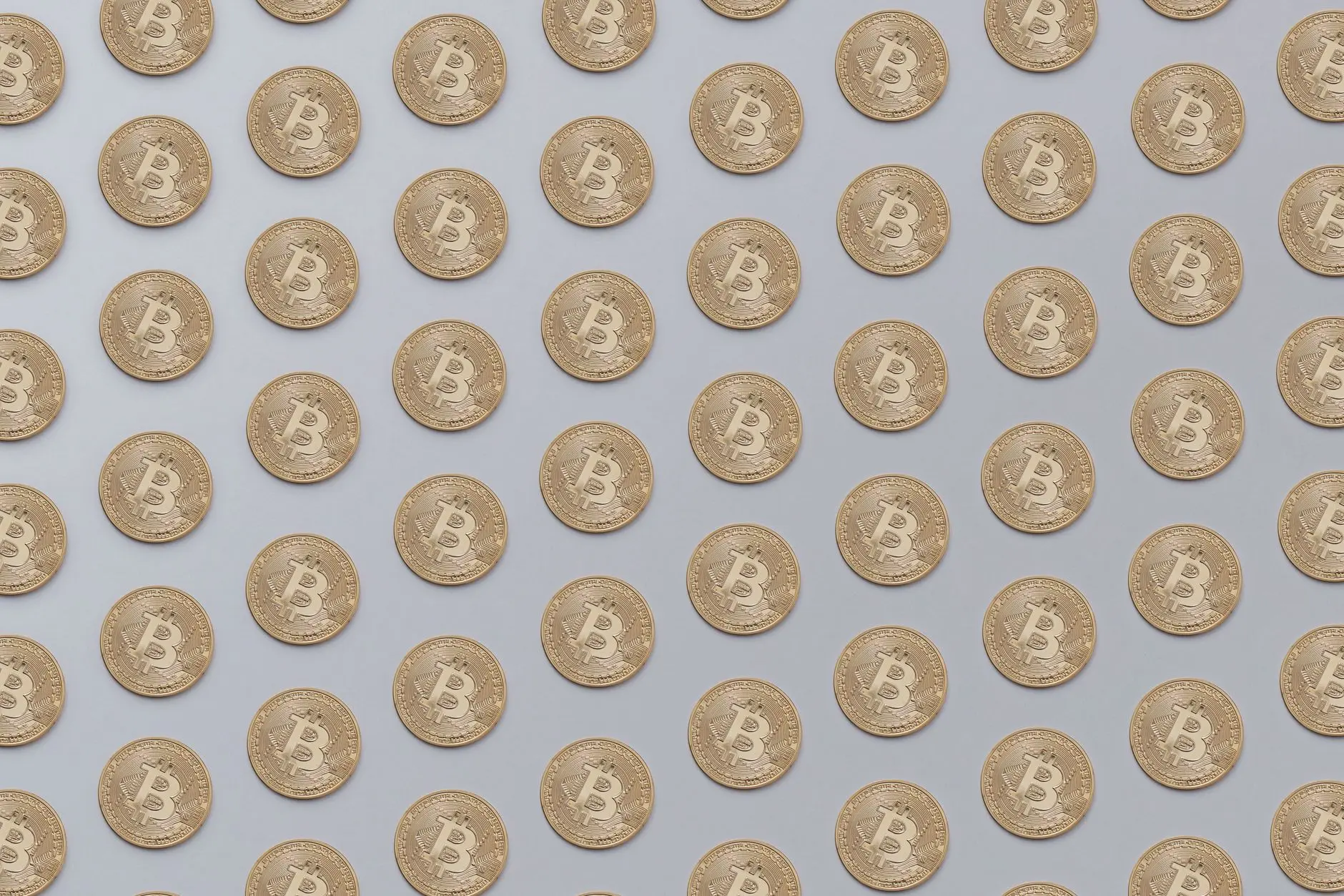 Pattern of Bitcoin coins arranged on a light background.