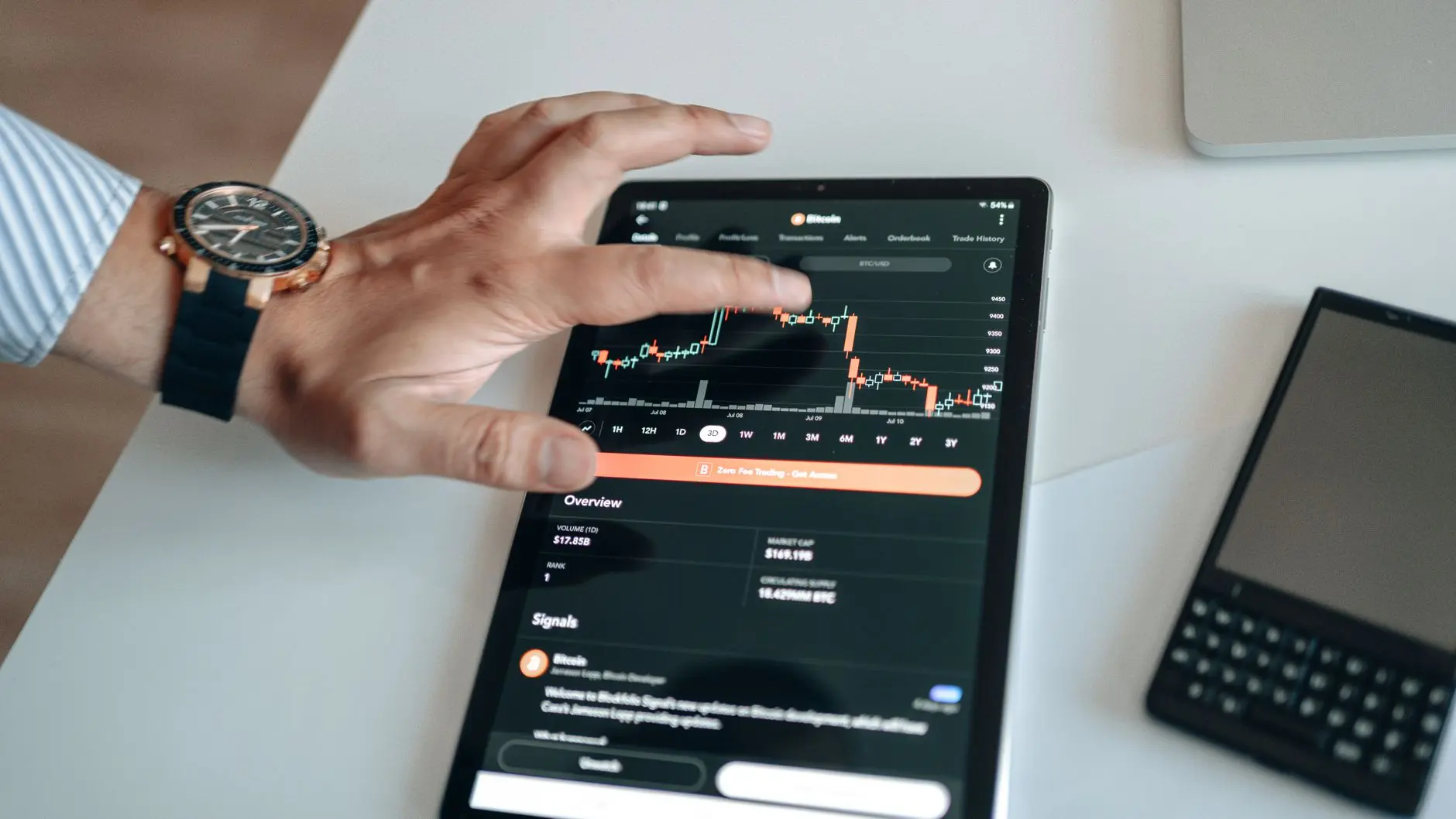 A hand interacting with cryptocurrency trading charts on a tablet screen.