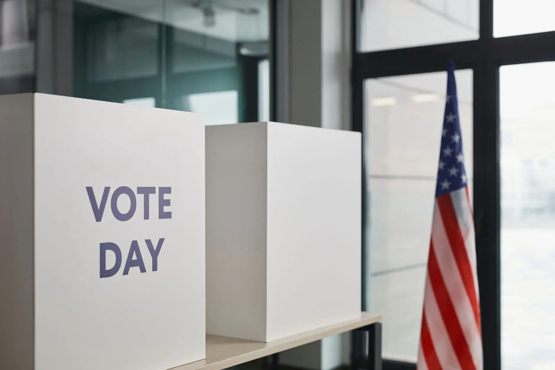 Voting booths labeled 'Vote Day' with an American flag in the background.