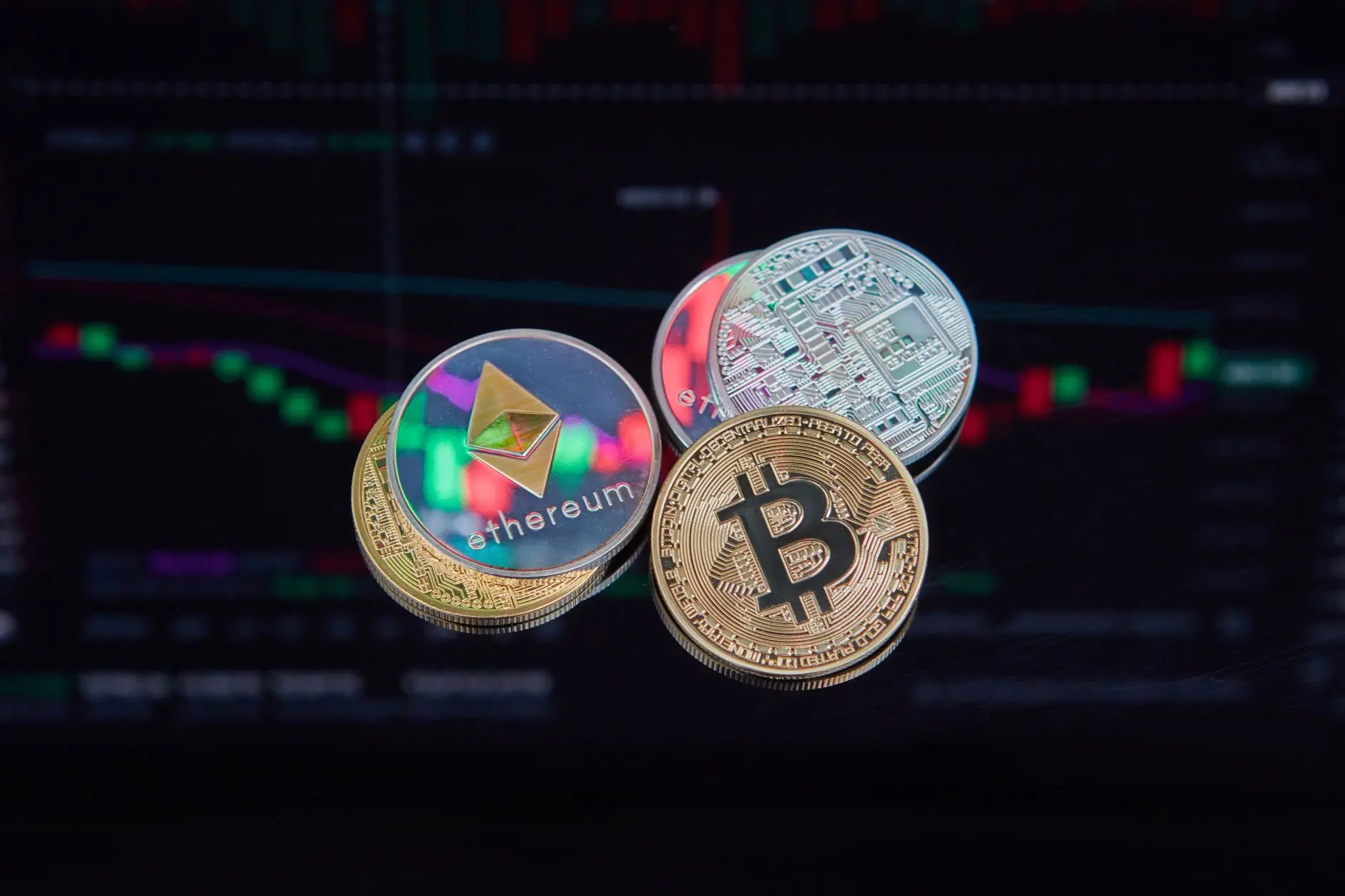 Bitcoin and Ethereum coins in front of a digital trading chart.