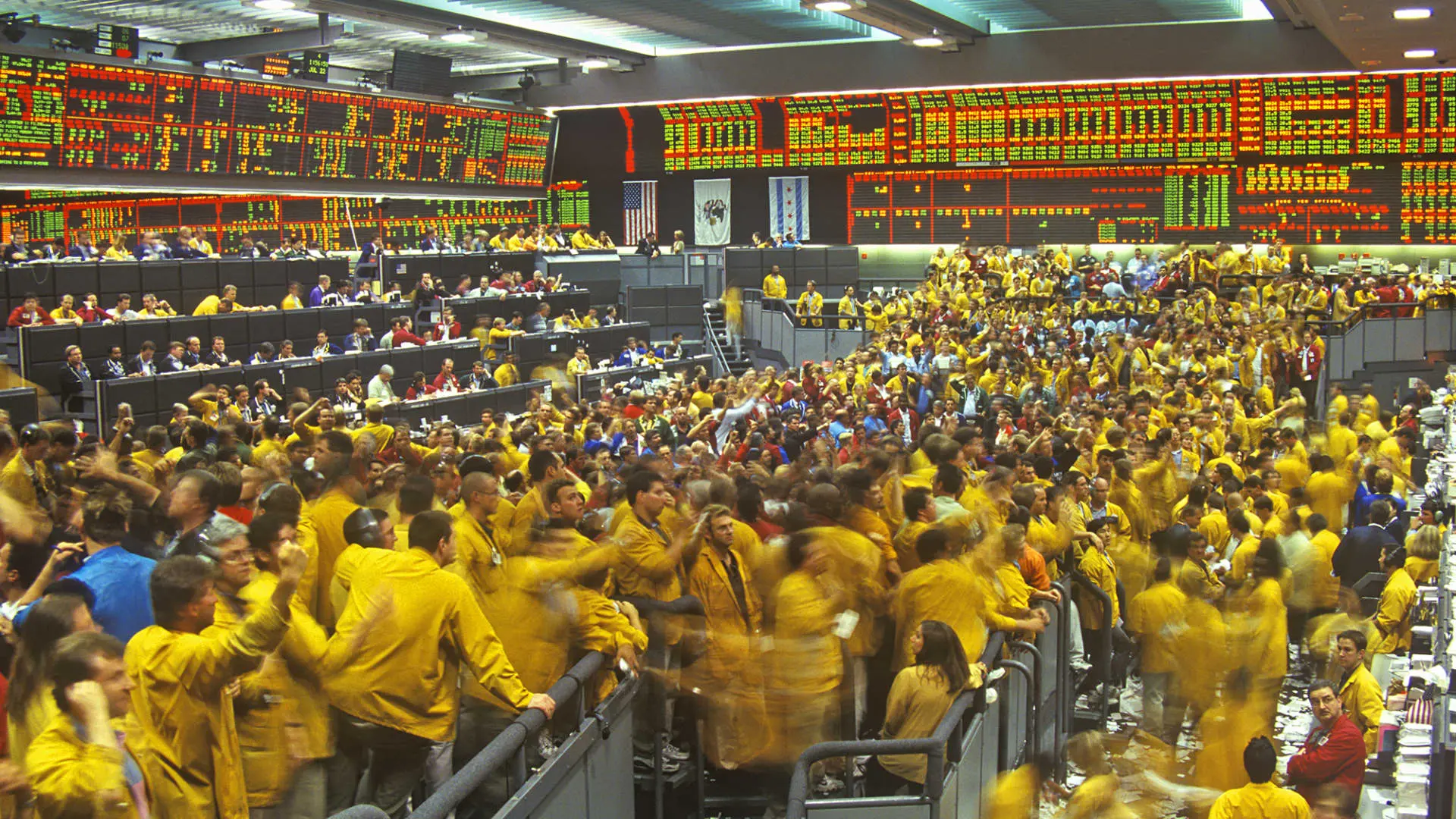 Crowded CME Group trading floor in Chicago with traders in yellow jackets actively trading.