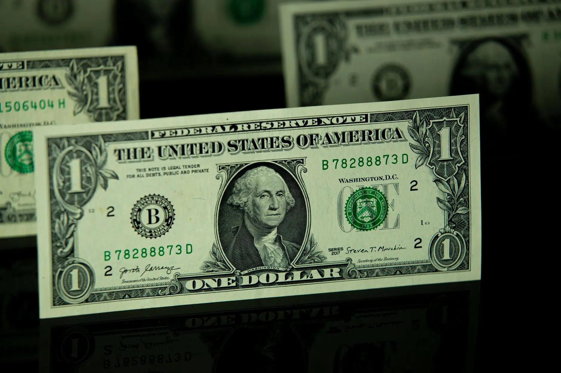 Close-up of a one US dollar bill on a reflective surface.