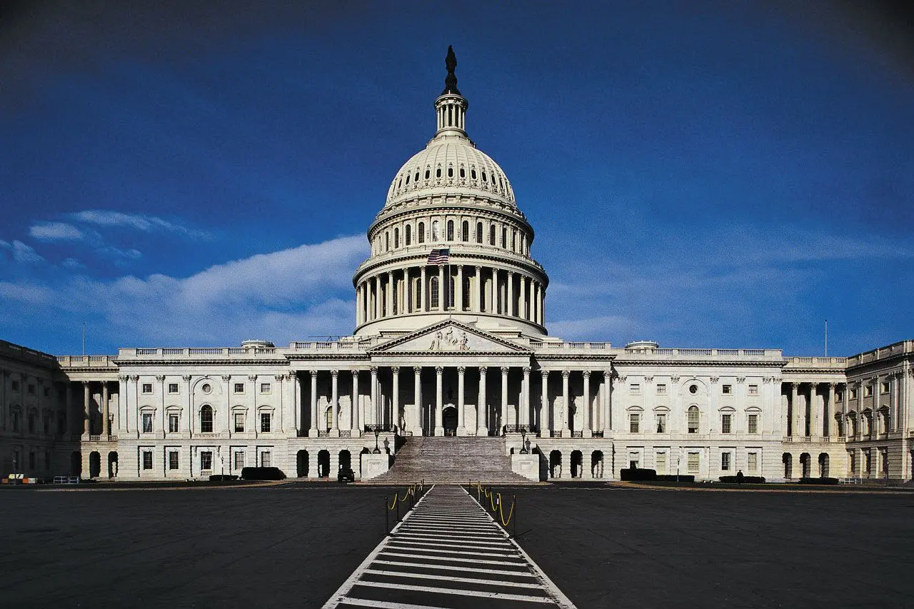 The US Capitol Building featuring its iconic dome and steps under a blue sky.