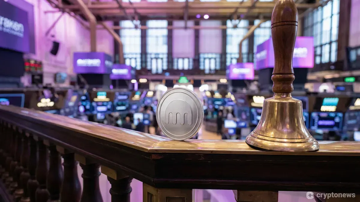 証券取引所のバルコニーにある上場のベルの横に置かれたクラーケンのロゴ入りコイン